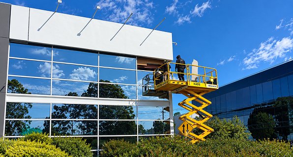 Technician working from a scissor lift on the glass facade of a commercial building