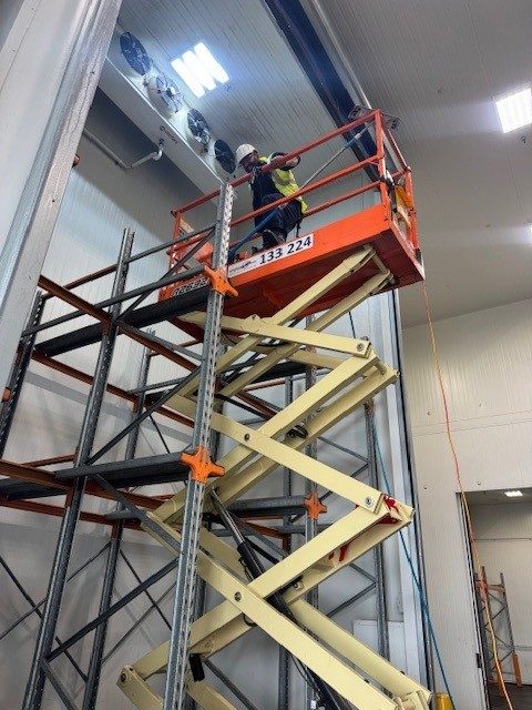 Technician on a scissor lift servicing coolroom fans