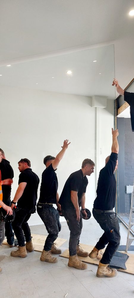 Team lifting a large glass panel into a shopfront