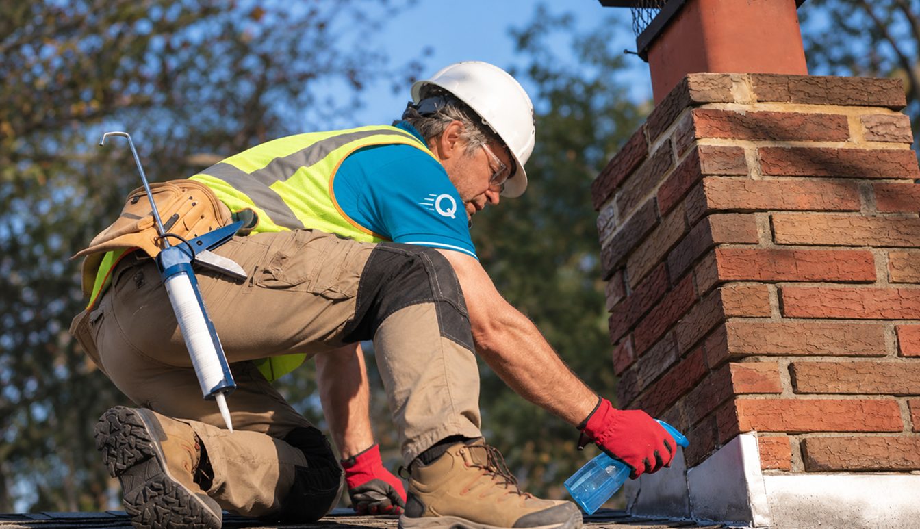 Quick Replace tradesperson sealing around a brick chimney on a roof