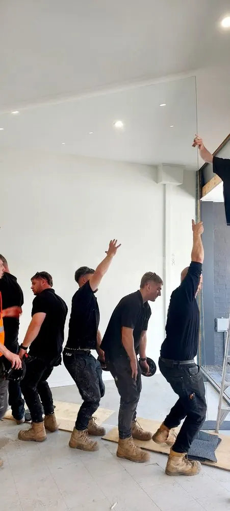 Team lifting a large glass panel into a shopfront