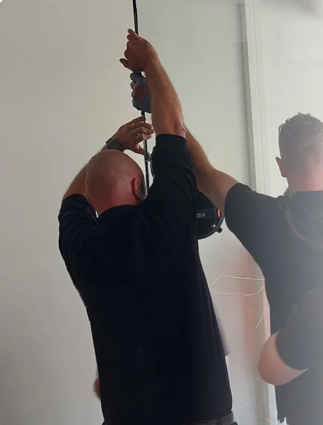 Technicians fitting a large glass panel