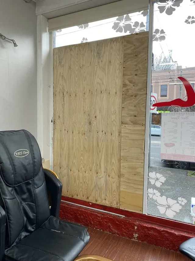 Salon window boarded with plywood from the inside