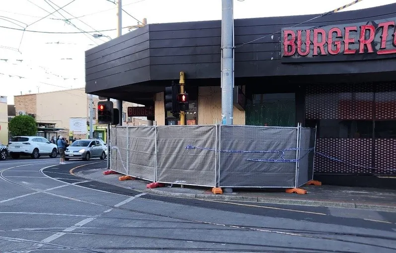 Temporary fencing set up around a damaged corner shopfront